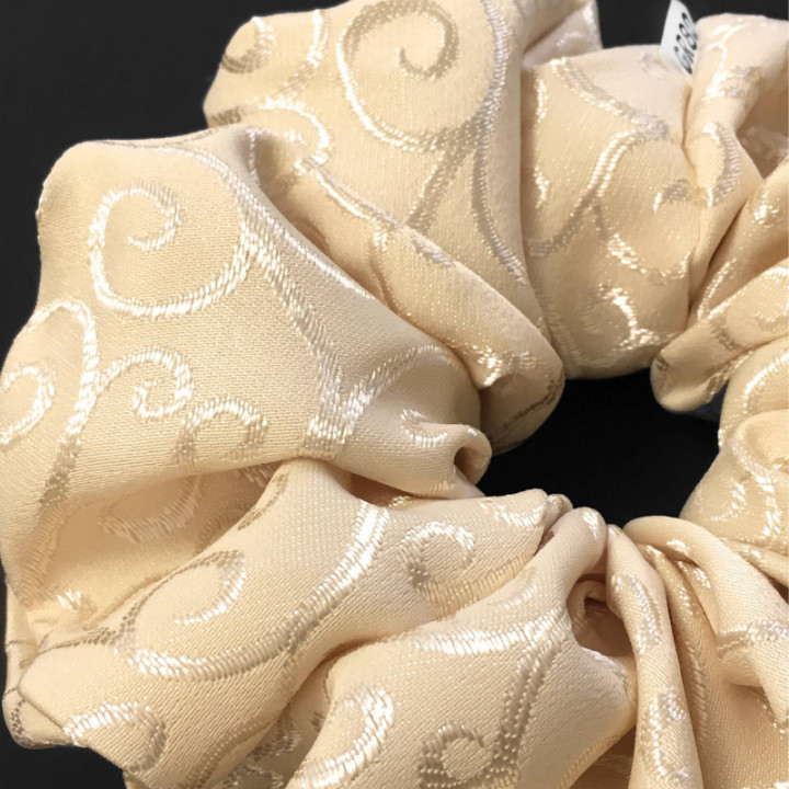 Óriás, inda mintával hímzett hajgumi (scrunchie) prémium minőségű anyagból. Átmérője kb. 16-17 cm. Ekrü/bézs szín